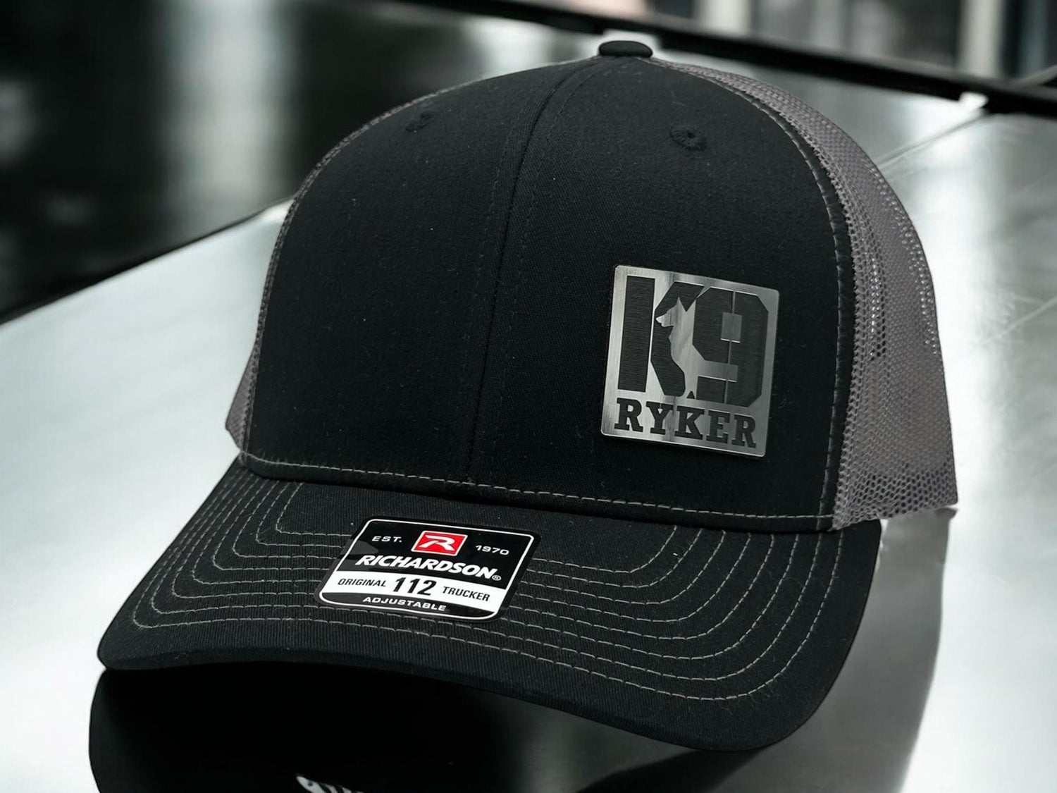 Black Richardson 112 trucker hat with a personalized K9 leather patch