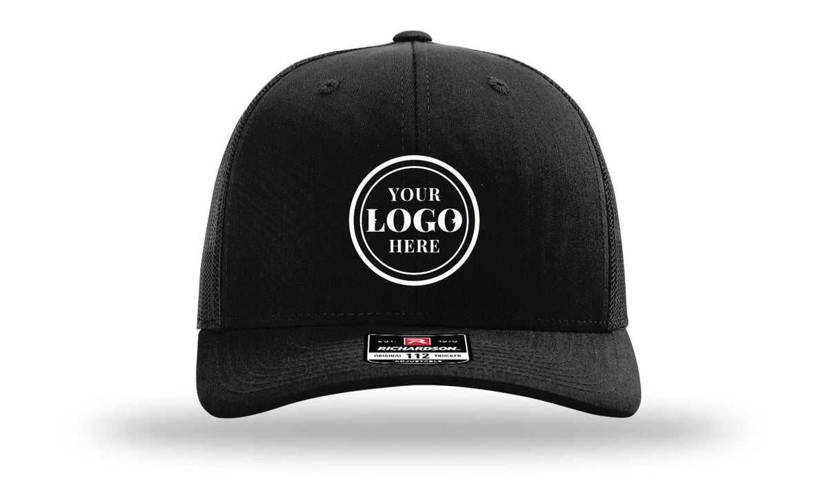 Richardson 112 trucker cap, black, with 2.1 in embroidered logo placeholder centered on front panel